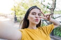 Young and beautiful caucasian girl make a selfie on a smartphone and showing a gesture of peace and a kiss. Royalty Free Stock Photo