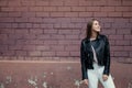 Young beautiful caucasian girl posing in a black leather jacket on a brick wall background. Royalty Free Stock Photo