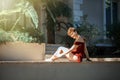 Young beautiful caucasian girl with short haircut in short red dress with naked hip sitting outdoors and smiling. Healthy relaxed Royalty Free Stock Photo