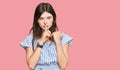 Young beautiful caucasian girl wearing casual clothes asking to be quiet with finger on lips pointing with hand to the side Royalty Free Stock Photo