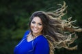 Young beautiful caucasian plus size model in blue dress outdoors, xxl woman on nature with developing in the wind hair Royalty Free Stock Photo