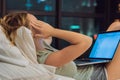 Young beautiful, caucasian, red haired, internet addicted woman working bored, sleepless and tired on her laptop in bed Royalty Free Stock Photo