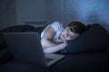 Young beautiful internet addicted sleepless and tired woman working on laptop in bed late at night Royalty Free Stock Photo