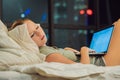 Young beautiful, caucasian, red haired, internet addicted woman working bored, sleepless and tired on her laptop in bed Royalty Free Stock Photo