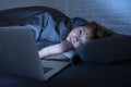 Young beautiful internet addicted sleepless and tired woman working on laptop in bed late at night Royalty Free Stock Photo