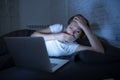 Young beautiful internet addicted sleepless and tired woman working on laptop in bed late at night Royalty Free Stock Photo