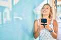 Young beautiful caucasian woman with blond hair smiling happy outdoors using smartphone Royalty Free Stock Photo