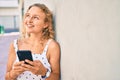 Young beautiful caucasian woman with blond hair smiling happy outdoors using smartphone Royalty Free Stock Photo