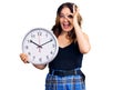 Young beautiful caucasian woman holding big clock smiling happy doing ok sign with hand on eye looking through fingers Royalty Free Stock Photo