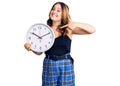 Young beautiful caucasian woman holding big clock smiling happy pointing with hand and finger Royalty Free Stock Photo