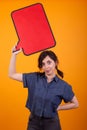 Young beautiful caucasian woman holding an empty tought bubble over her in studio over yellow background