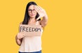 Young beautiful caucasian woman holding freedom banner with open hand doing stop sign with serious and confident expression,