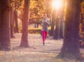 Young beautiful caucasian woman jogging workout training. Autumn running fitness girl in city urban park environment