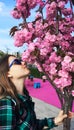 Young beautiful caucasian woman in profile in sunglasses sniffing pink sakura flowers. Spring blossom