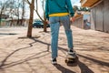 Young beautiful Caucasian woman rides a skateboard.The view from the back. In the background, a street with trees. Close up. Royalty Free Stock Photo