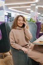 Young beautiful Caucasian woman is talking on a mobile phone, laughing, chatting. Cheerful hipster girl with curly hair using a Royalty Free Stock Photo