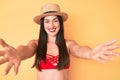 Young beautiful caucasian woman wearing bikini and hat looking at the camera smiling with open arms for hug Royalty Free Stock Photo