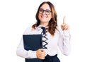 Young beautiful caucasian woman wearing business shirt and glasses holding folder surprised with an idea or question pointing Royalty Free Stock Photo