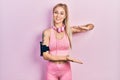 Young beautiful caucasian woman wearing gym clothes and using headphones gesturing with hands showing big and large size sign, Royalty Free Stock Photo