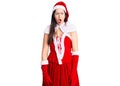 Young beautiful caucasian woman wearing santa claus costume in shock face, looking skeptical and sarcastic, surprised with open Royalty Free Stock Photo