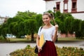 Young beautiful cheerful female student smiling, holding folders outdoors, park background. Royalty Free Stock Photo