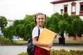 Young beautiful cheerful female student smiling, holding folders outdoors, park background. Royalty Free Stock Photo