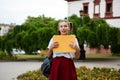 Young beautiful cheerful female student smiling, holding folders outdoors, park background. Royalty Free Stock Photo