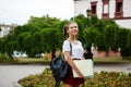 Young beautiful cheerful female student smiling, holding folders outdoors, park background. Royalty Free Stock Photo