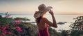 Young beautiful cheerful woman in bikini and hat enjoying tropical vacation with sea view at sunset Royalty Free Stock Photo