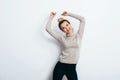 Young beautiful cheerful woman with hair bun wearing in jeans and sweater dancing and posing over white wall. Good mood. People Royalty Free Stock Photo