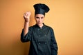 Young beautiful chef woman wearing cooker uniform and hat standing over yellow background Doing Italian gesture with hand and Royalty Free Stock Photo