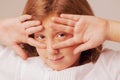 Young beautiful child girl looking through fingers as a symbol of trickery and deceit