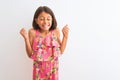 Young beautiful child girl wearing pink floral dress standing over isolated white background excited for success with arms raised Royalty Free Stock Photo