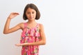 Young beautiful child girl wearing pink floral dress standing over isolated white background gesturing with hands showing big and Royalty Free Stock Photo