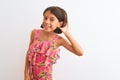 Young beautiful child girl wearing pink floral dress standing over isolated white background smiling with hand over ear listening Royalty Free Stock Photo