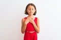 Young beautiful child girl wearing red casual dress standing over isolated white background smiling with hands on chest with Royalty Free Stock Photo