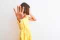 Young beautiful child girl wearing yellow floral dress standing over isolated white background covering eyes with hands and doing Royalty Free Stock Photo