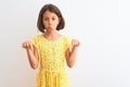 Young beautiful child girl wearing yellow floral dress standing over isolated white background Pointing down looking sad and Royalty Free Stock Photo