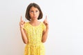 Young beautiful child girl wearing yellow floral dress standing over isolated white background Pointing up looking sad and upset, Royalty Free Stock Photo