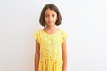 Young beautiful child girl wearing yellow floral dress standing over isolated white background Relaxed with serious expression on Royalty Free Stock Photo