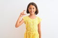 Young beautiful child girl wearing yellow floral dress standing over isolated white background smiling and confident gesturing Royalty Free Stock Photo