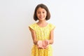 Young beautiful child girl wearing yellow floral dress standing over isolated white background Smiling with hands palms together Royalty Free Stock Photo