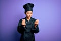 Young beautiful chinese chef woman wearing cooker uniform and hat over purple background doing money gesture with hands, asking Royalty Free Stock Photo