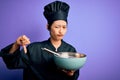 Young beautiful chinese chef woman wearing cooker uniform and hat using bowl and whisk with angry face, negative sign showing Royalty Free Stock Photo