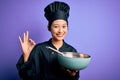 Young beautiful chinese chef woman wearing cooker uniform and hat using bowl and whisk doing ok sign with fingers, excellent Royalty Free Stock Photo