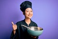 Young beautiful chinese chef woman wearing cooker uniform and hat using bowl and whisk happy with big smile doing ok sign, thumb Royalty Free Stock Photo