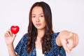 Young beautiful chinese girl holding heart pointing with finger to the camera and to you, confident gesture looking serious Royalty Free Stock Photo