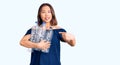 Young beautiful chinese girl holding recycling plastic bottles smiling happy pointing with hand and finger