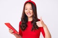 Young beautiful chinese girl holding touchpad smiling happy and positive, thumb up doing excellent and approval sign Royalty Free Stock Photo
