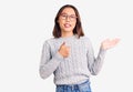 Young beautiful chinese girl wearing casual clothes showing palm hand and doing ok gesture with thumbs up, smiling happy and Royalty Free Stock Photo